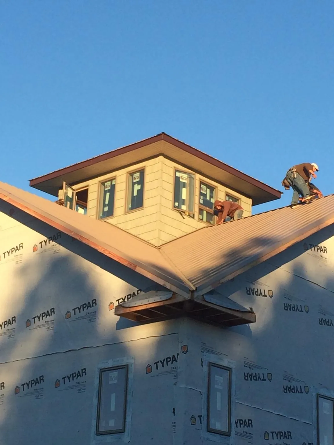 Roofers working around a rooftop cupola on a new metal roof at sunset — Roof Waterproofing in Camden by Roofing Brothers